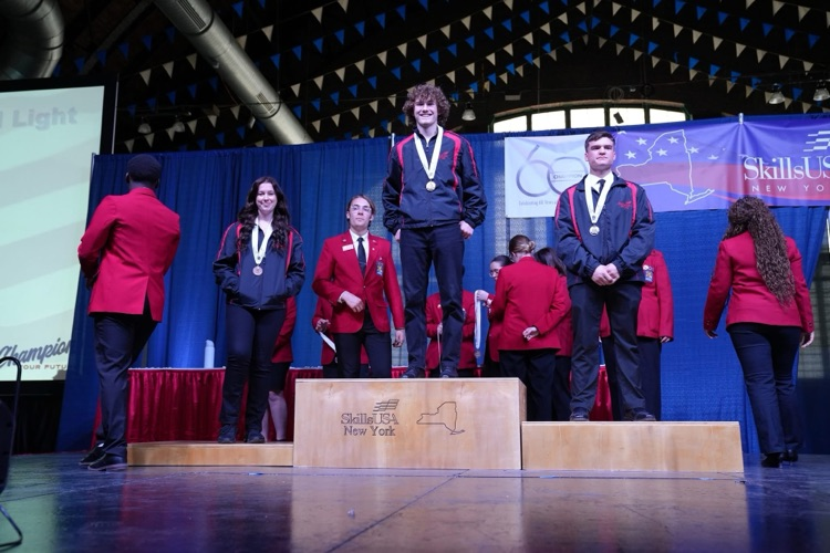 Jackson Scholl, gold medalist standing on podium smiling at camera 
