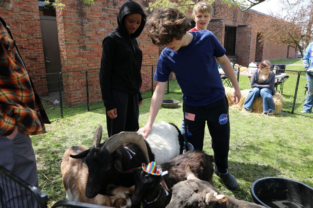 three students petting a goat