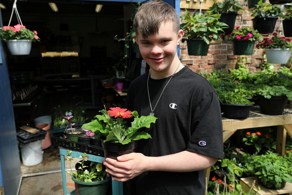 a student holding up a flower plant for the camera