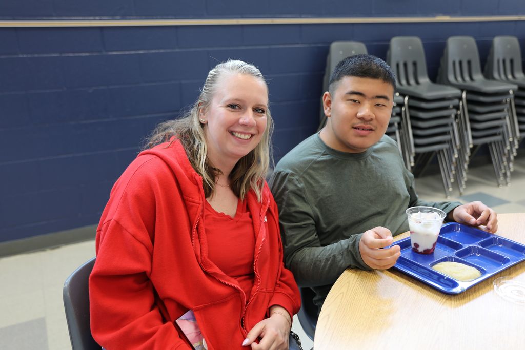 a student and staff member smiling at camera