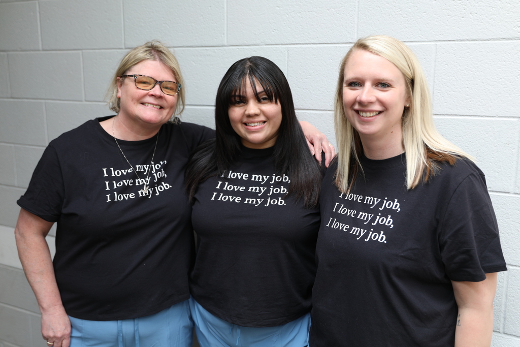 Three staff members posing for camera with the same shirt 
