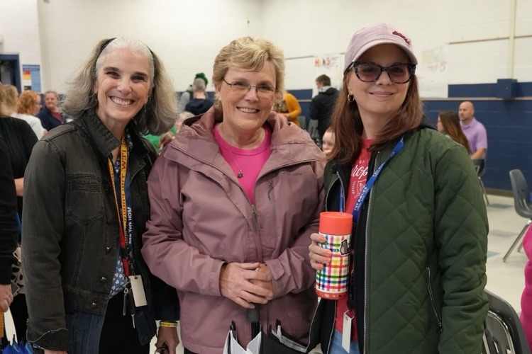 CTE teachers and staff stand together smiling  in the cafeteria at the staff appreaciation breakfast