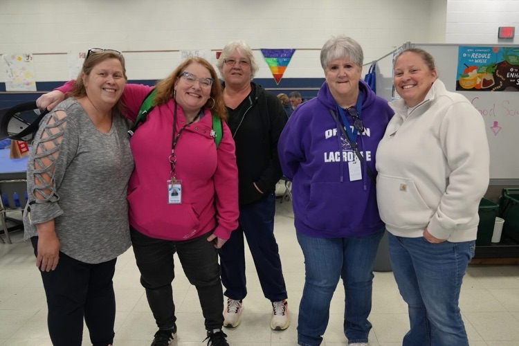 Smith School teachers and staff stand together smiling the cafeteria at the staff appreaciation breakfast