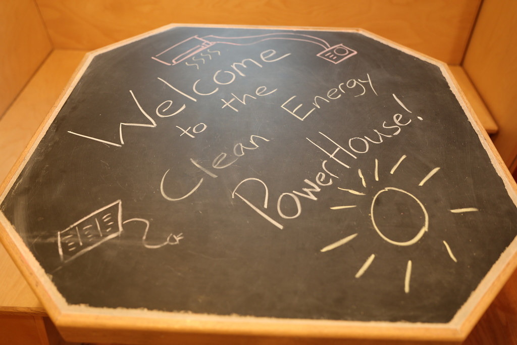 A chalkboard table saying "Welcome to the Clean Energy PowerHouse"