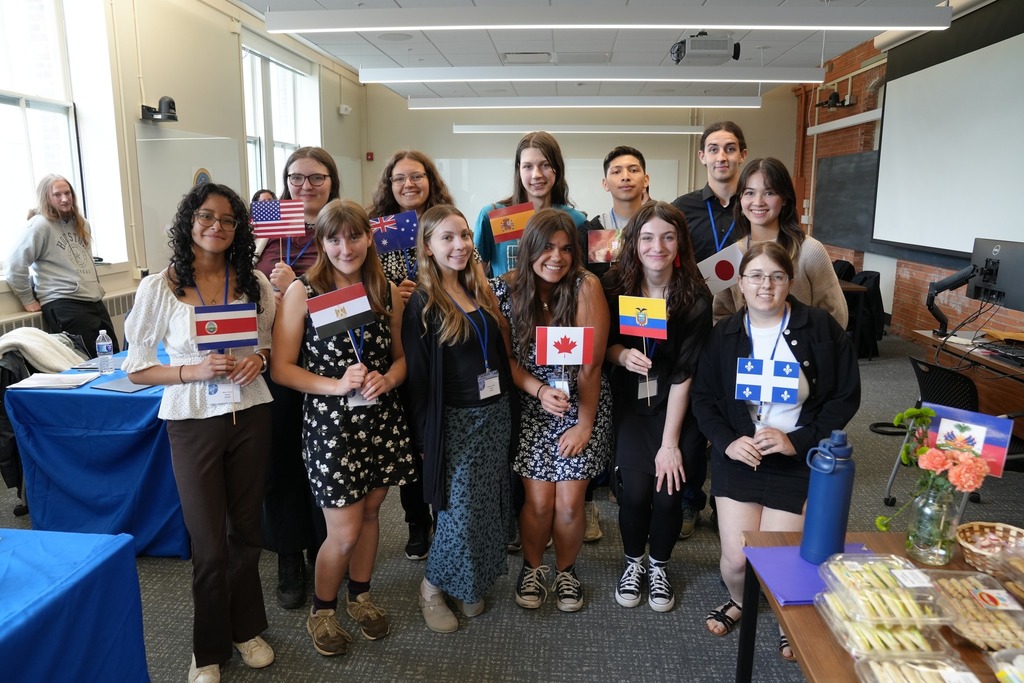 Students from Dryden and Lansing CSD pose together during the Regional Seal of Biliteracy Presentation Day, with several students holding flags representing different languages and cultures.