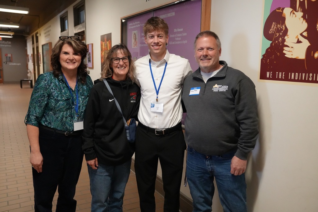 A student participant poses with family member, Groton Superintendent and Groton French teacher in a hallway during the Seal of Biliteracy Presentation Day.