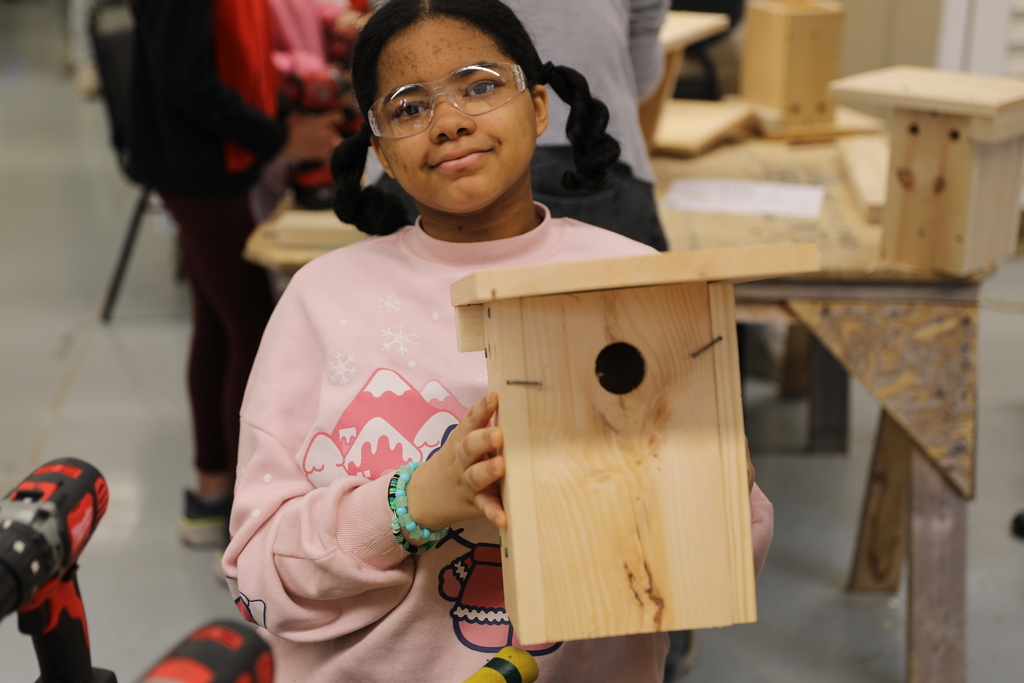 a student holding up her bird house 