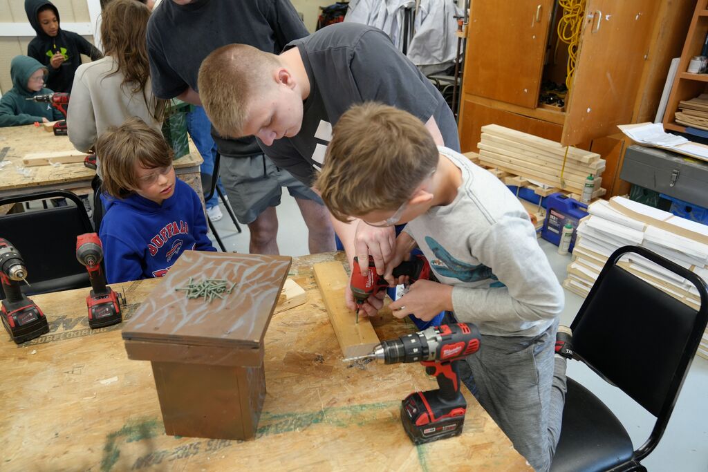 two younger students and one older student putting together a bird house
