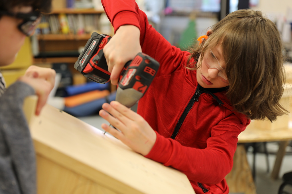 a close up of one student drilling into a bird house