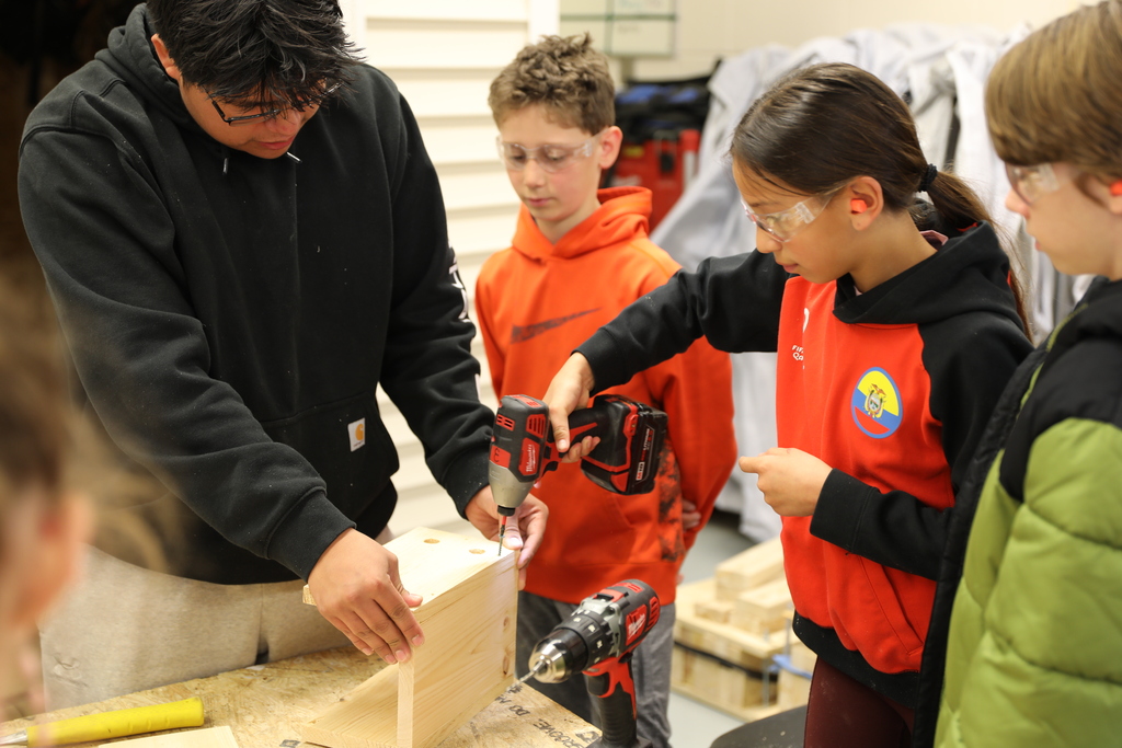 three young students building a bird house with an older student