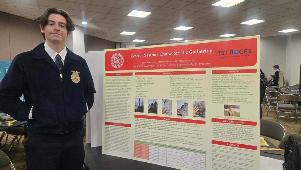 John Feenan stands beside his Agriscience Fair presentation on kestrel nestbox characteristics during the New York State FFA Convention.
