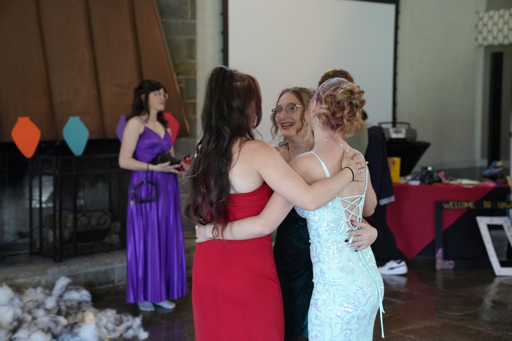 Students in formal attire share a group hug while dancing at the Turning Point Program’s annual dinner dance at Cornell’s Moakley House.