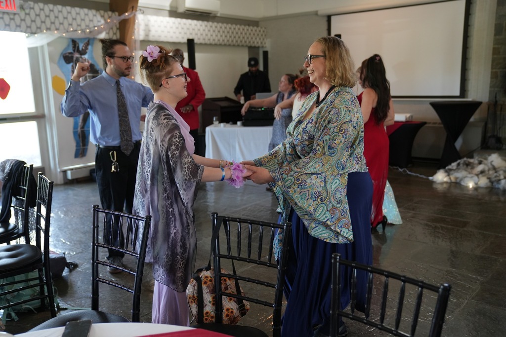 A student and adult dance together and smile on the dance floor during the Turning Point Program’s annual dinner dance.