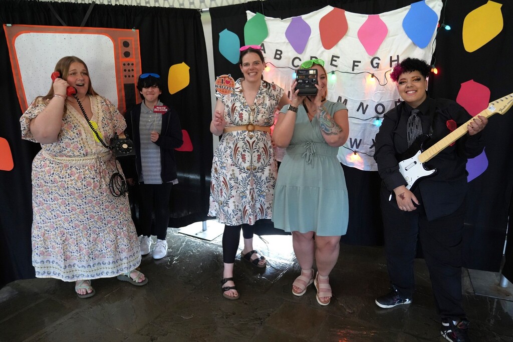 Staff members and students pose together with retro props in the Stranger Things-themed photo booth at the annual dinner dance.