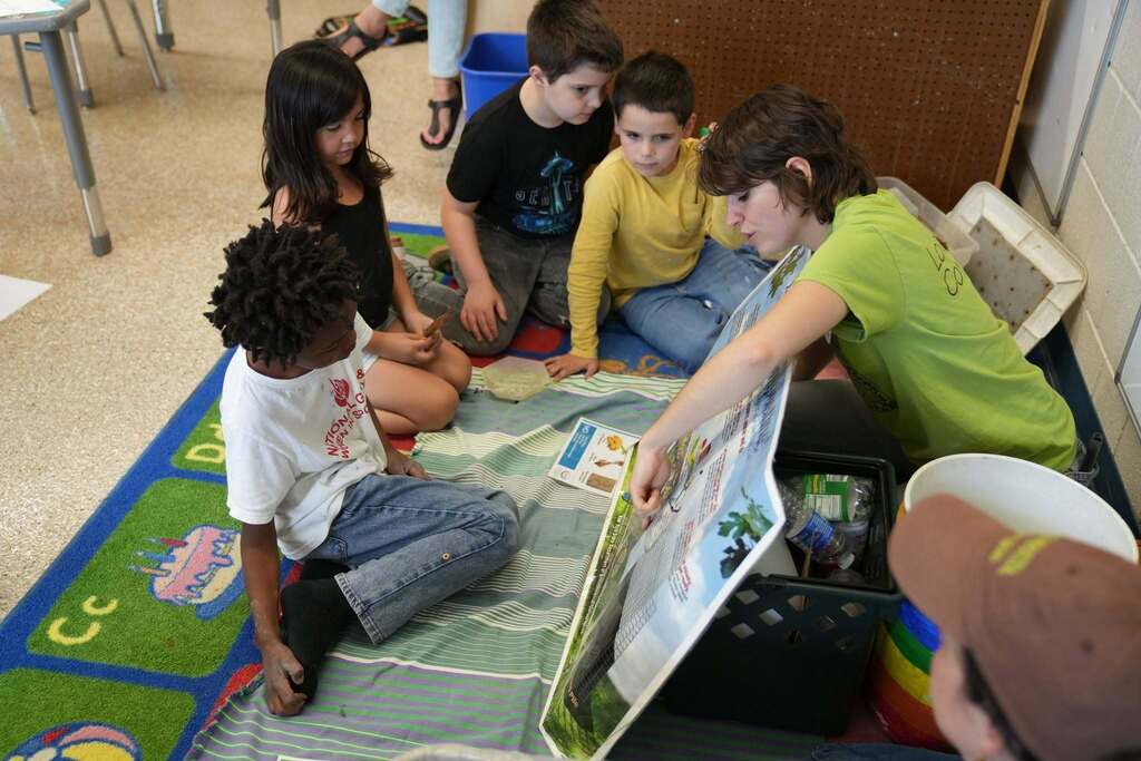 A Cornell Cooperative Extension educator uses an educational display board to teach students about composting and waste reduction during a classroom lesson.