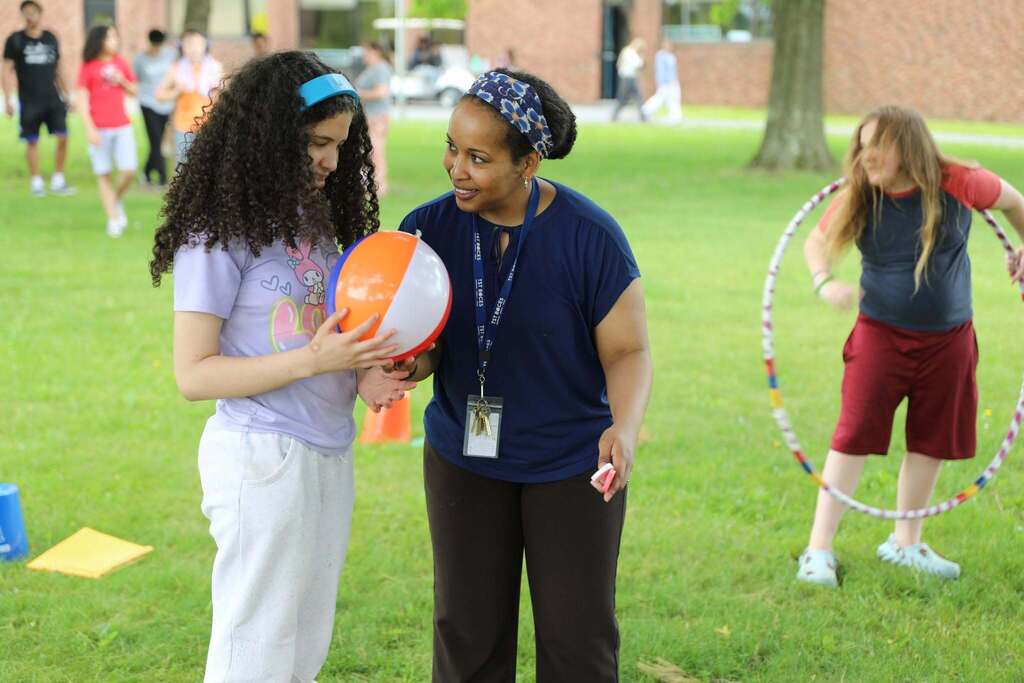 a staff member and student playing with a beach ball