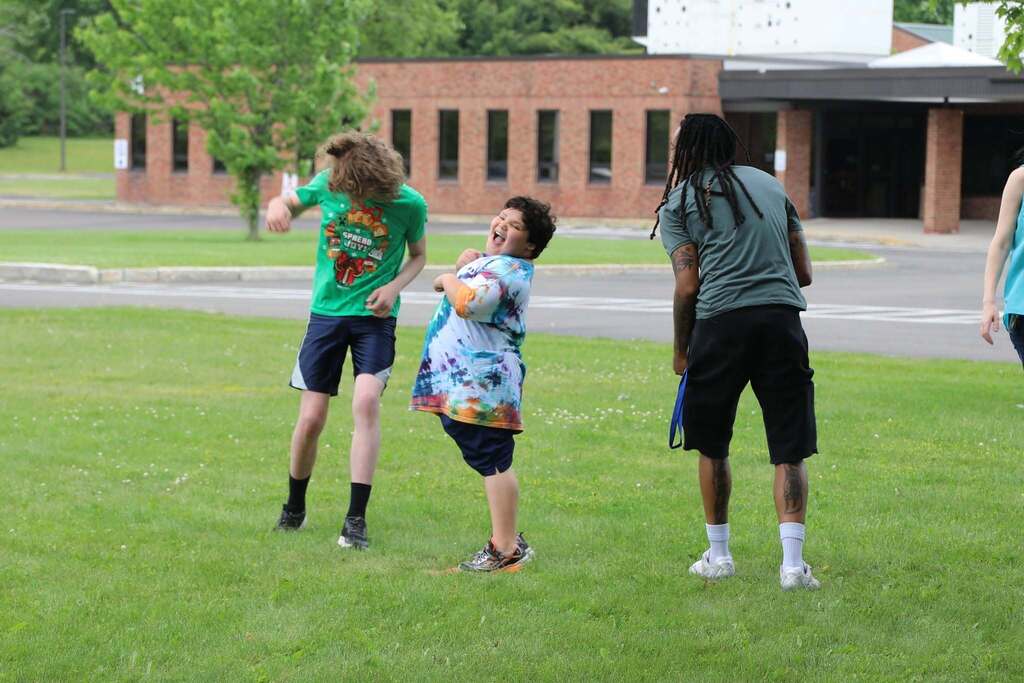 Two students and a staff member playing kickball