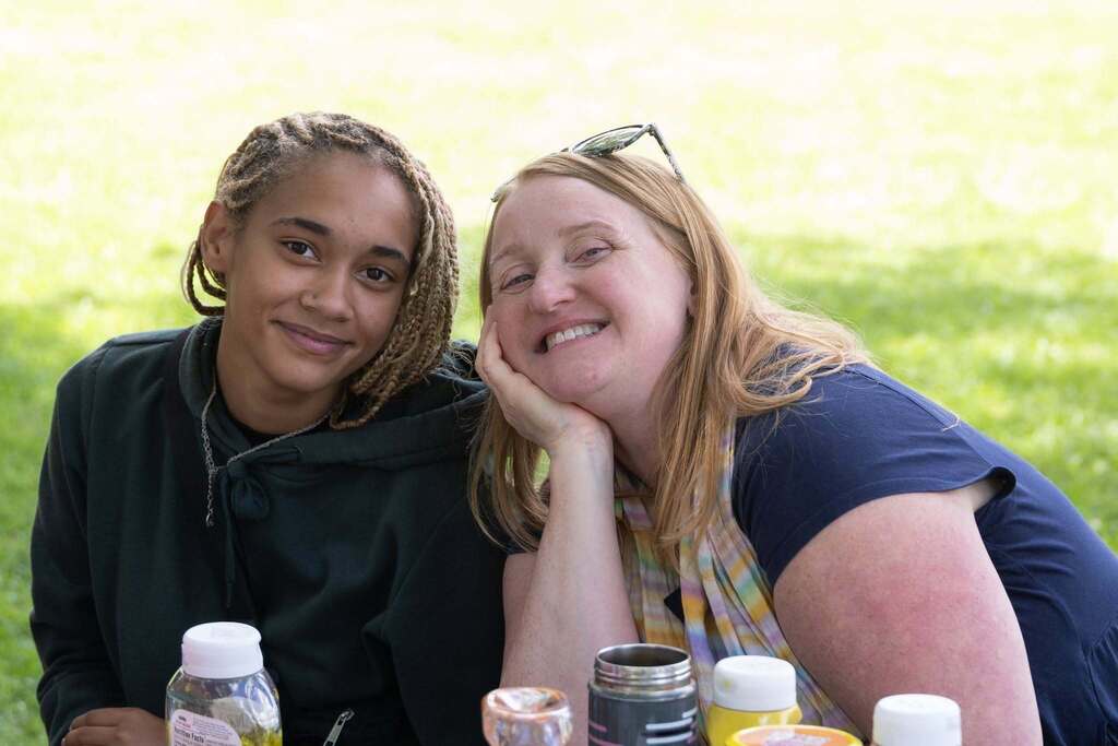 Student and staff member smile together while seated at a picnic table during the Turning Point end-of-year celebration.