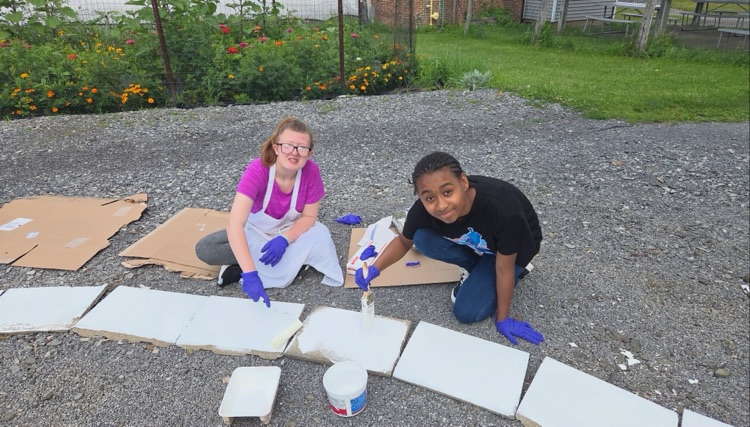 Summer School students work together outdoors to paint concrete pavers for the Circle of Courage labyrinth in the Smith School garden.
