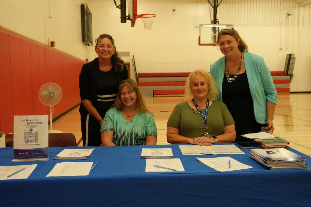 Members of the Regional School Success team welcome attendees at the conference registration table with programs, sign-in sheets, and conference materials.