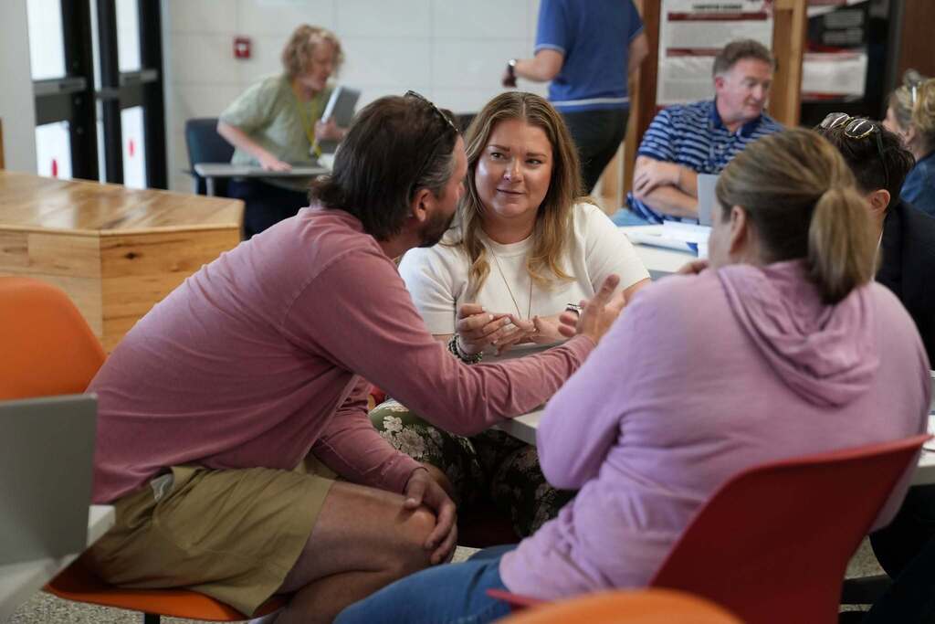 Educational leaders sit around a table in small groups, discussing ideas and collaborating during a breakout session at the Regional Administrator AI Conference.
