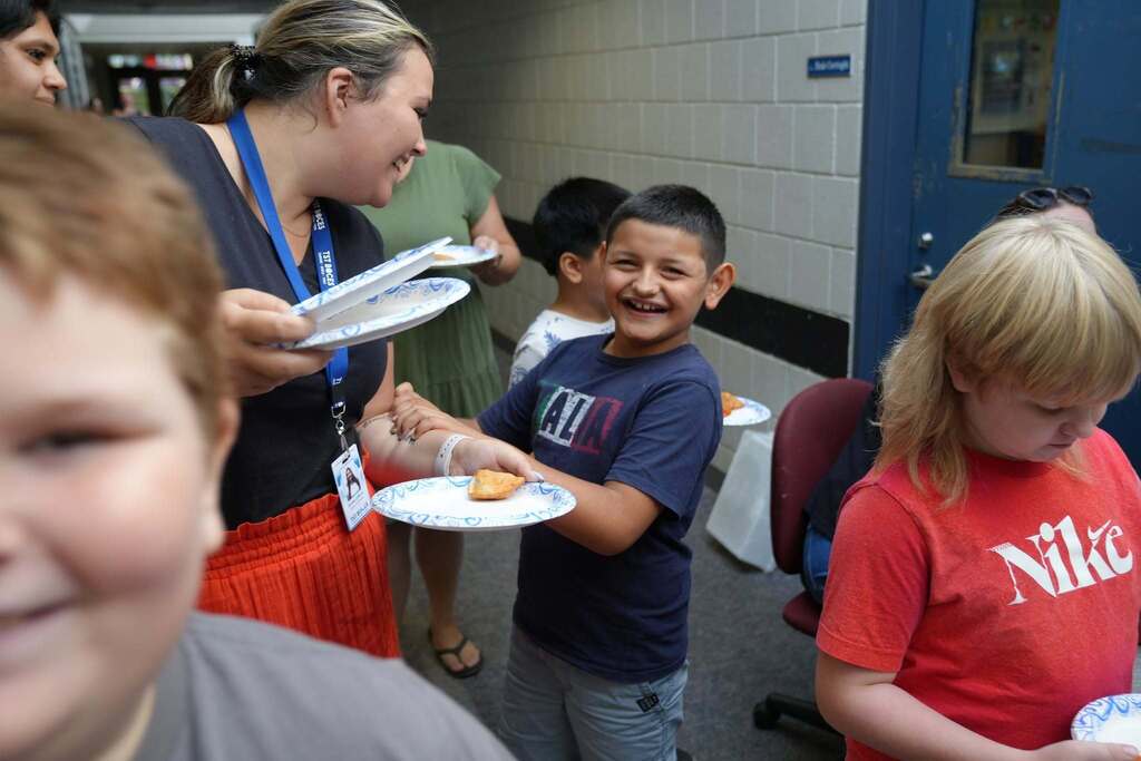 A smiling Summer School student holds a plate with a food sample while talking with a staff member during the World Cup Flavor event.