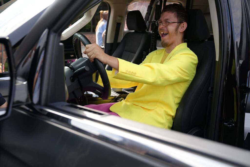 A student wearing a bright yellow jacket laughs while exploring the driver’s seat of a police vehicle during Community Day.