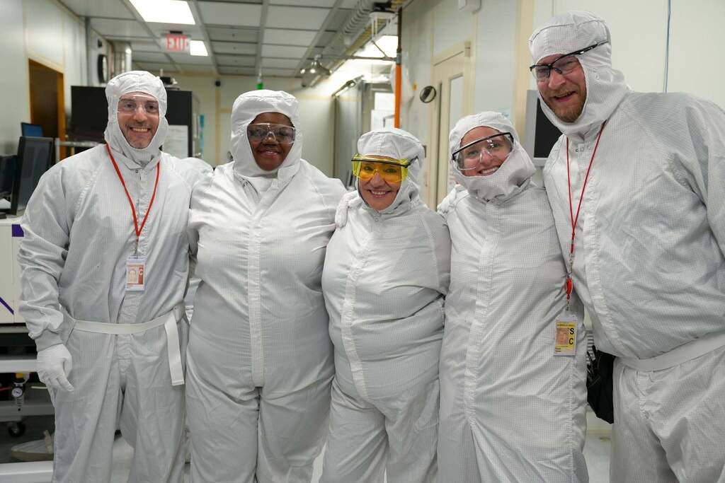 Commissioner Rosa, Assembly Member Dr. Anna Kelles and Senator Lea webb, and other visitors pose with Cornell NanoScale Science and Technology Facility staff while wearing cleanroom suits during the facility tour.