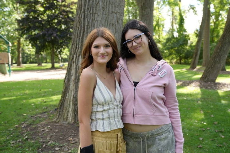 two teenage girls pose and smile at camera while surrounded by trees at Myers park picnic 
