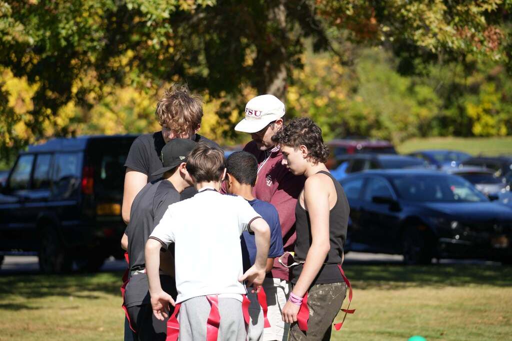 RAS students gathered in a huddle for flag football strategy with their coach