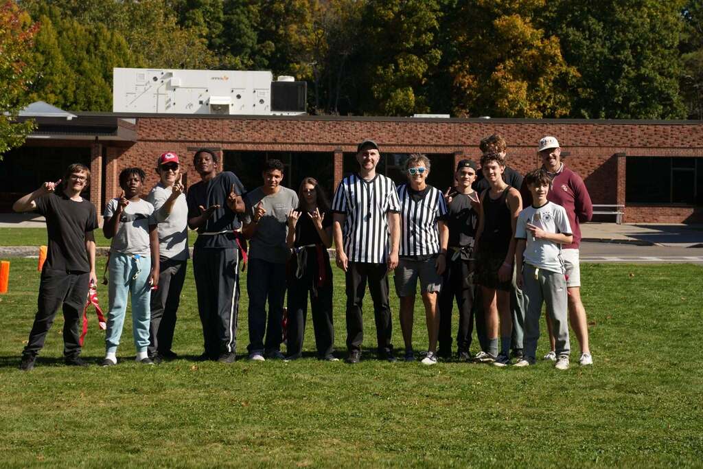 both teams and officials stand and pose on the field at the end of the RAS flag football game