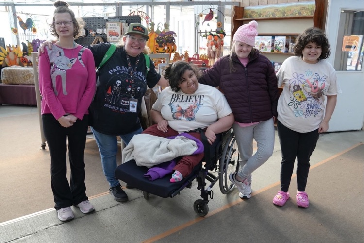 Four students and one staff member pose with arms around each other and smile in the gift shop on class field trip