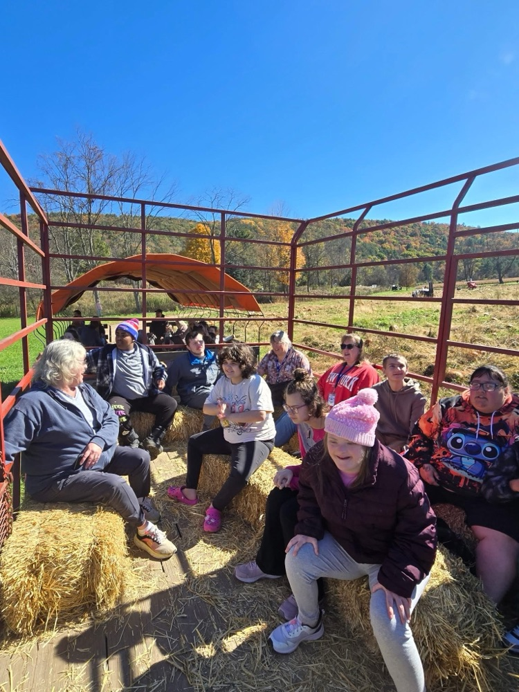 classes sit on hay wagon and take a ride on field trip to the pumpkin patch