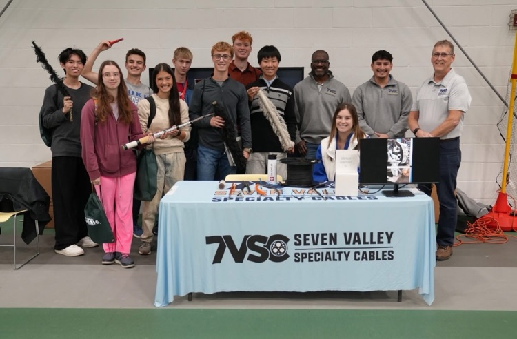 Students from TST BOCES NV Engineering engaging with hands-on displays and industry exhibits at the "How It's Made" Expo at Tompkins Cortland Community College. The students stand with Seven Valley specialty cables  employees and smile at camera 