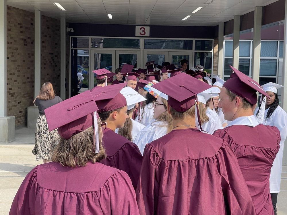 Image of seniors from behind in their caps and gowns, walking into the building
