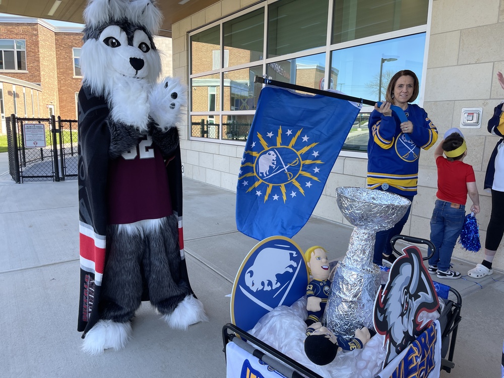 Tonawanda mascot claps with teacher waving sabres flag and handmade stanley cup