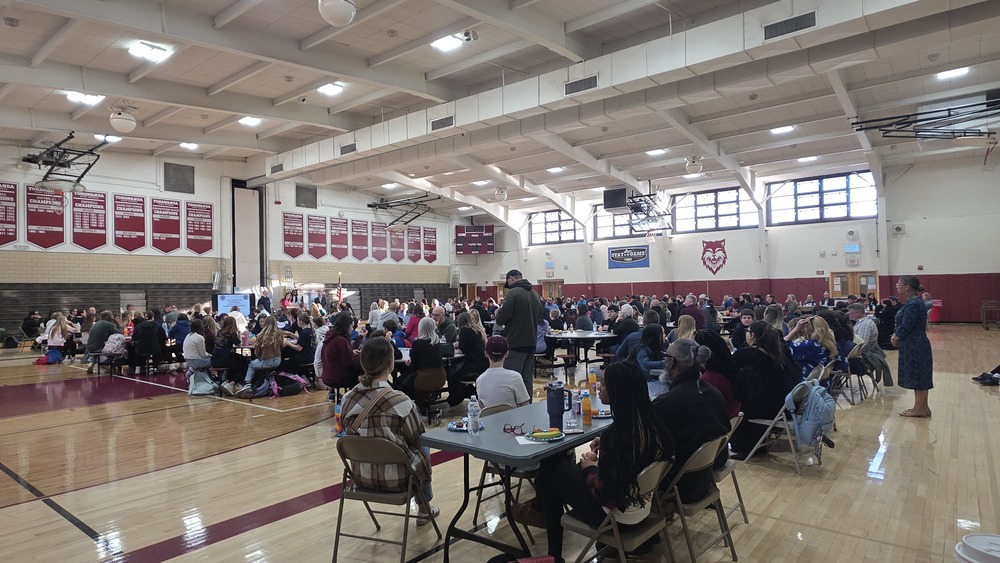 families and students gathered at tables in gym for breakfast