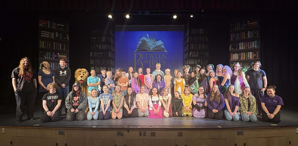 cast of between the lines poses on stage