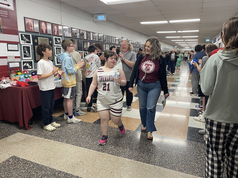 students and staff lining hallways, cheering for unified basketball team