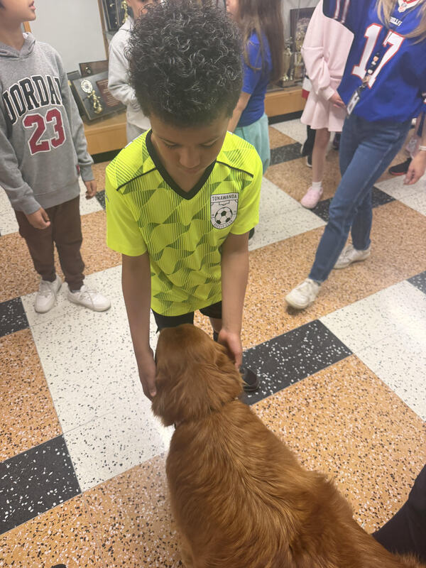 student leans down to pet dog's head