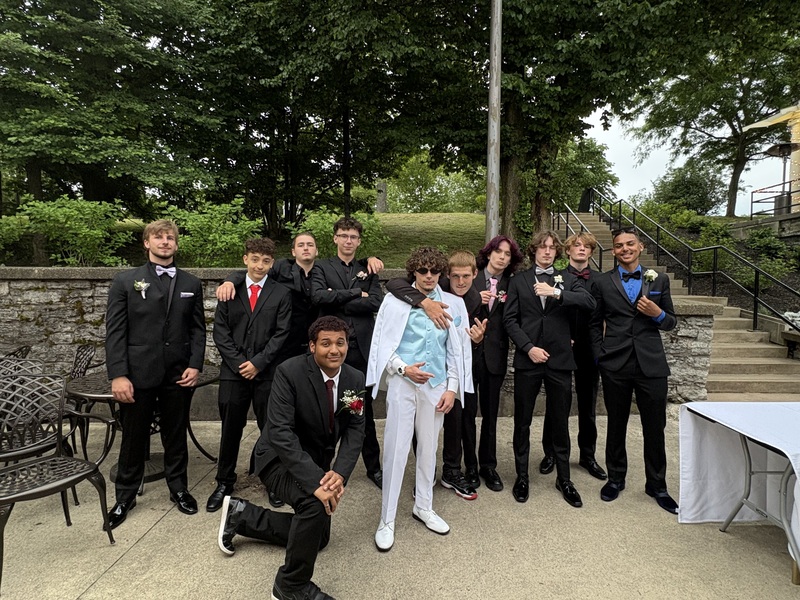 students pose in front of stone wall and trees in courtyard