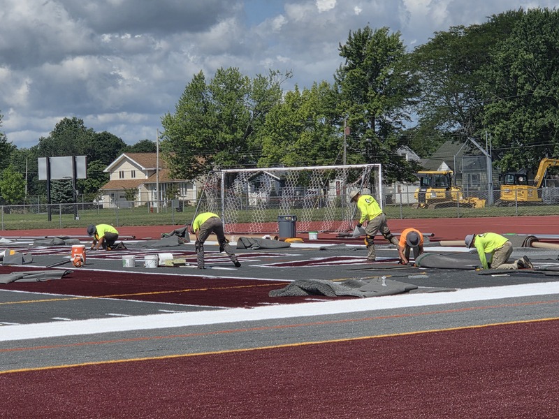 workers installing turf in end zone