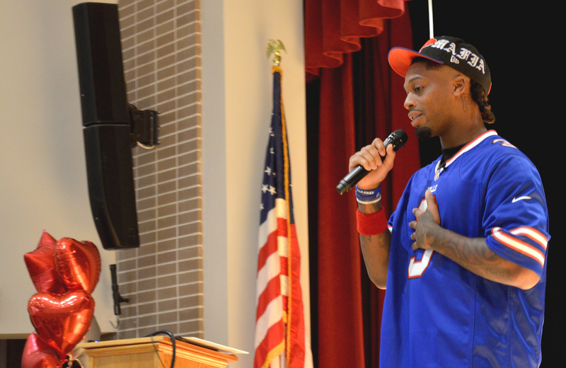 damar hamlin speaking on stage with flag in background
