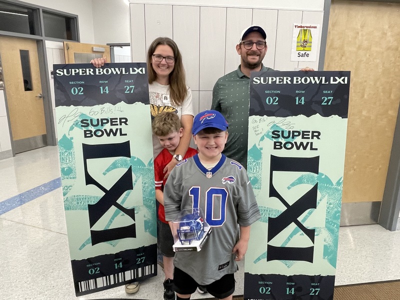 family poses with superbowl tickets