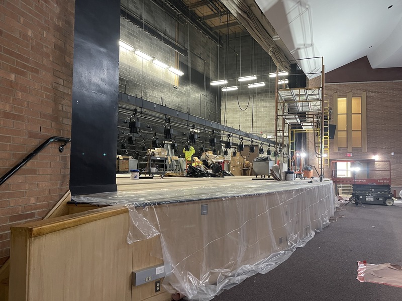 wide shot of auditorium stage with lights and construction materials all over it