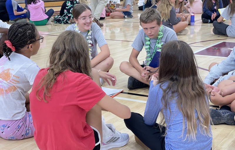students sitting in group on gym floor