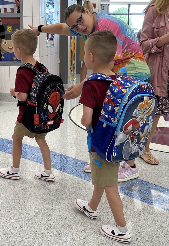 teacher guides student to their classroom
