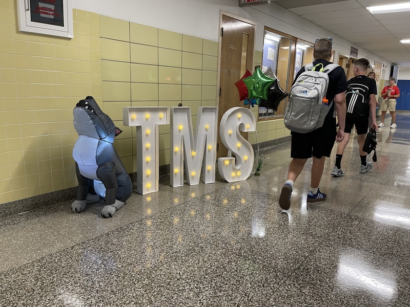 students walk past TMS sign on the way to cafeteria