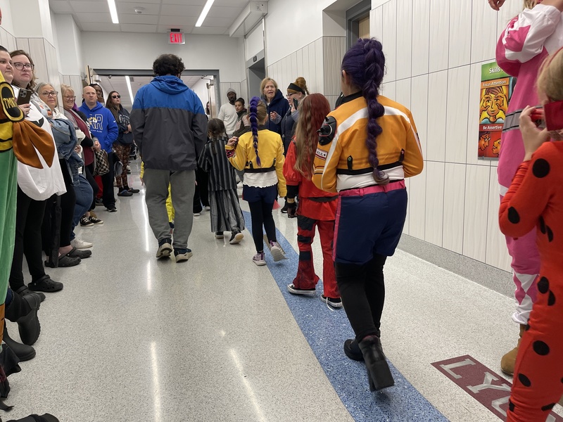 students walk the halls of the school in costume for the halloween parade