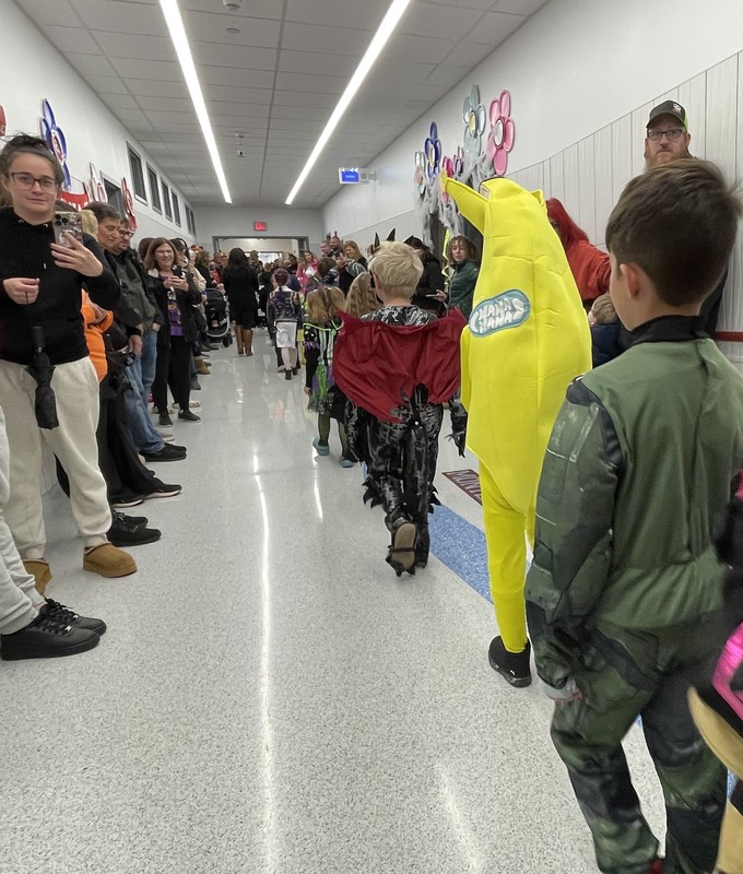 students walk the halls of the school in costume for the halloween parade